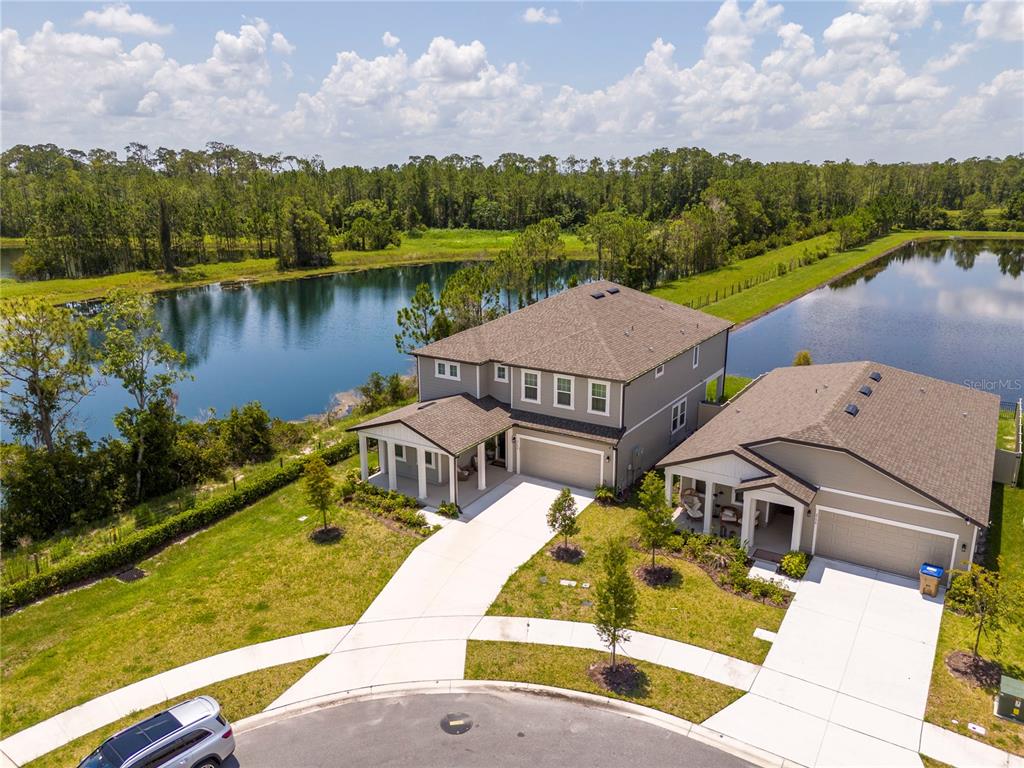 An aerial view shows two suburban houses with driveways situated next to a large pond — 2184 BROADBROOK DRIVE, ST CLOUD, FL