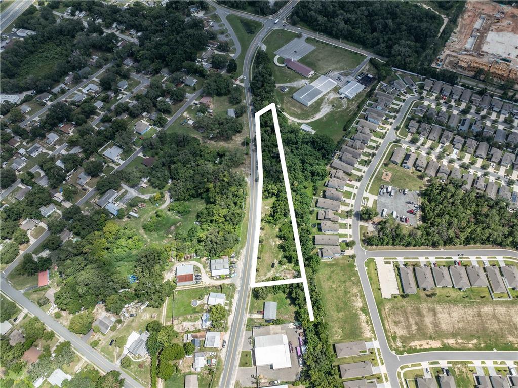 An aerial view shows a long, narrow, undeveloped plot of land outlined in white — 801 S DIXIE AVENUE UNIT A, FRUITLAND PARK, FL