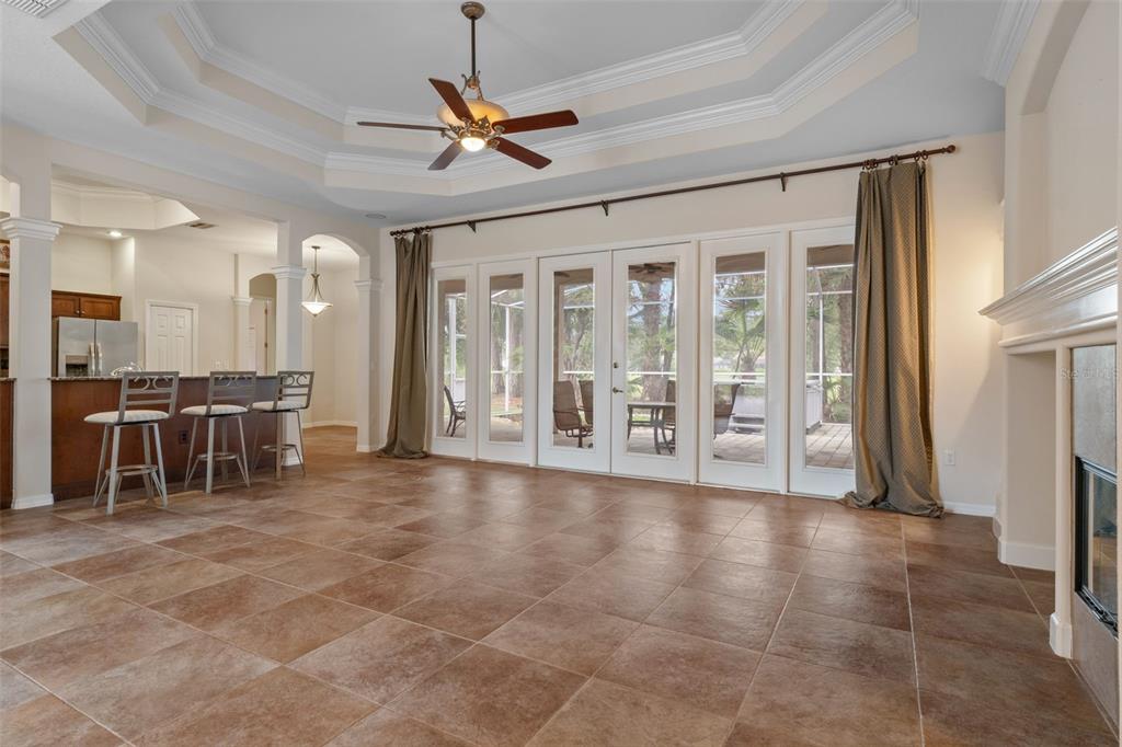 A living room with tile flooring, a tray ceiling, and glass doors leading to a patio — 5141 CHAMPIONSHIP CUP LANE, SPRING HILL, FL