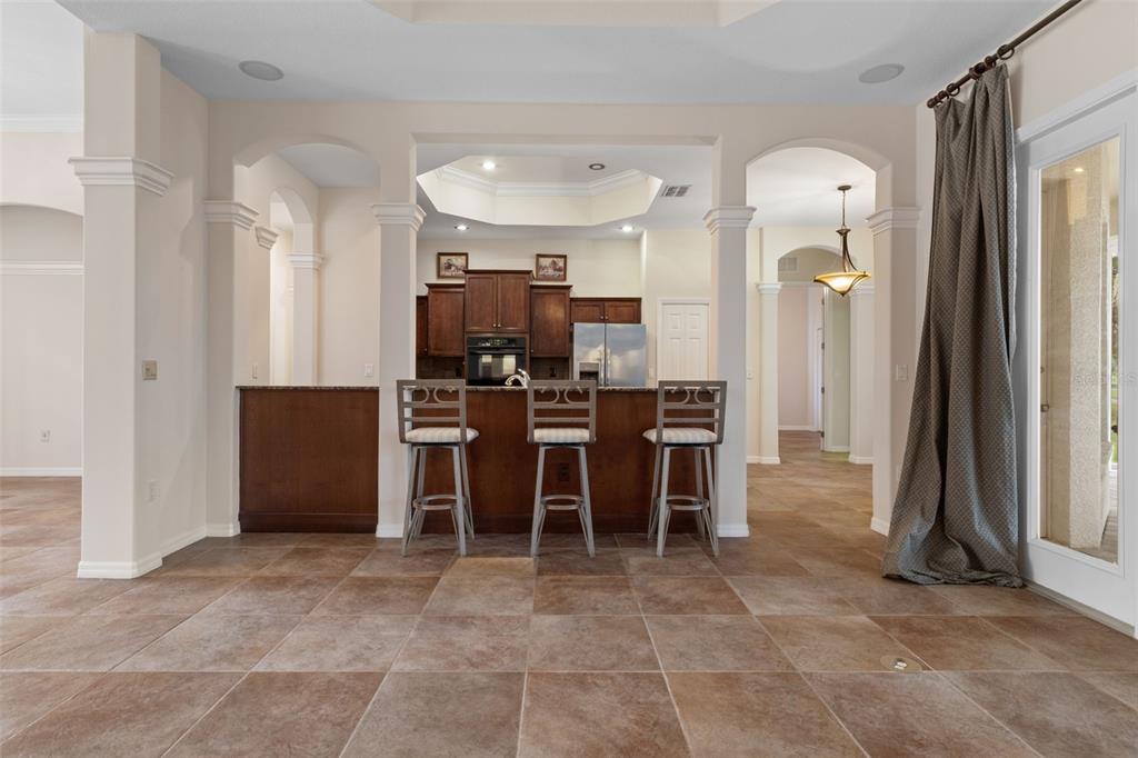 A kitchen with dark wood cabinets and a breakfast bar sits behind a tiled floor — 5141 CHAMPIONSHIP CUP LANE, SPRING HILL, FL