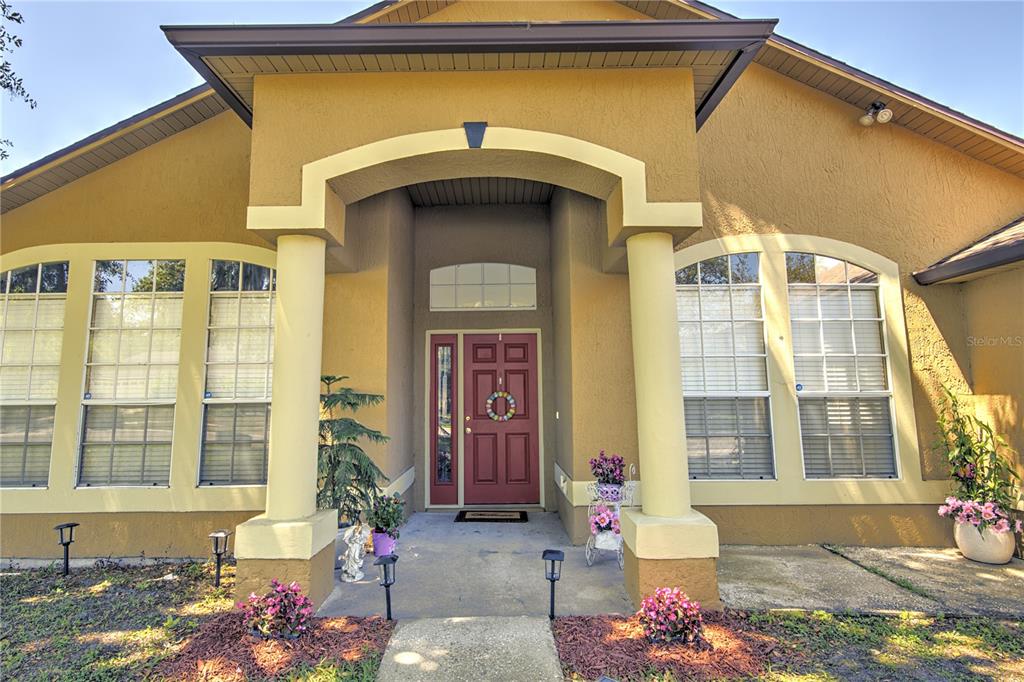 A tan stucco house features a covered entryway with two columns and a red door — 684 YORKSHIRE DRIVE, OVIEDO, FL