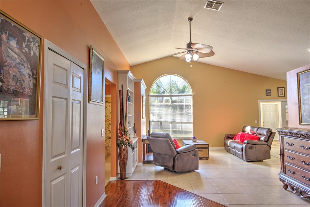 A living room features vaulted ceilings, tile and wood flooring, a ceiling fan, and windows — 684 YORKSHIRE DRIVE, OVIEDO, FL