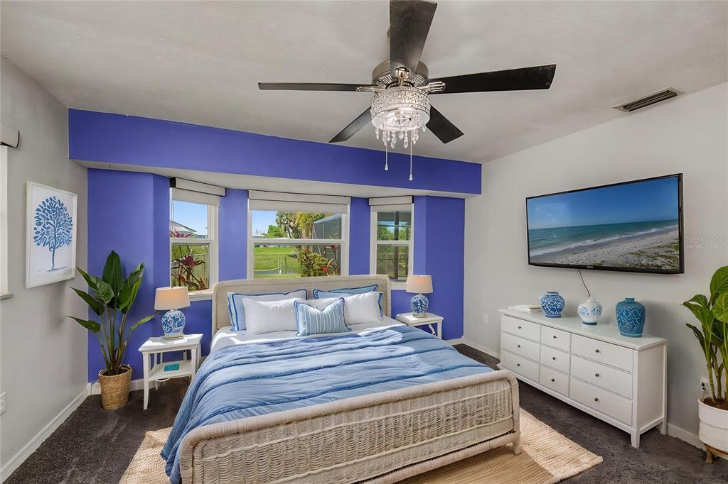 A living room features a fireplace, wicker furniture, and sliding glass doors overlooking a pool — 2479 ACHILLES STREET, PUNTA GORDA, FL