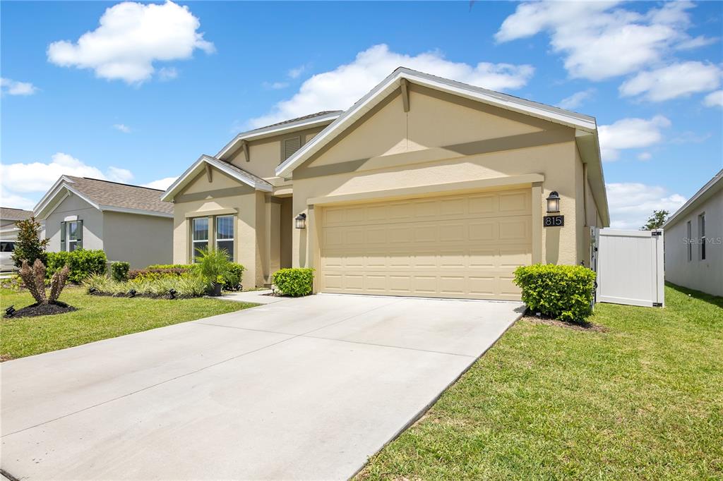 A tan, single-story suburban house with a two-car garage and a concrete driveway — 815 KAPI DRIVE, GROVELAND, FL