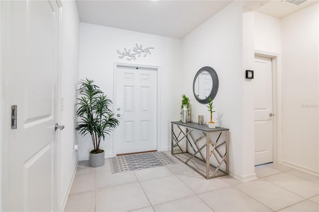 A bright entryway features white walls, tile flooring, a console table, and a front door — 815 KAPI DRIVE, GROVELAND, FL