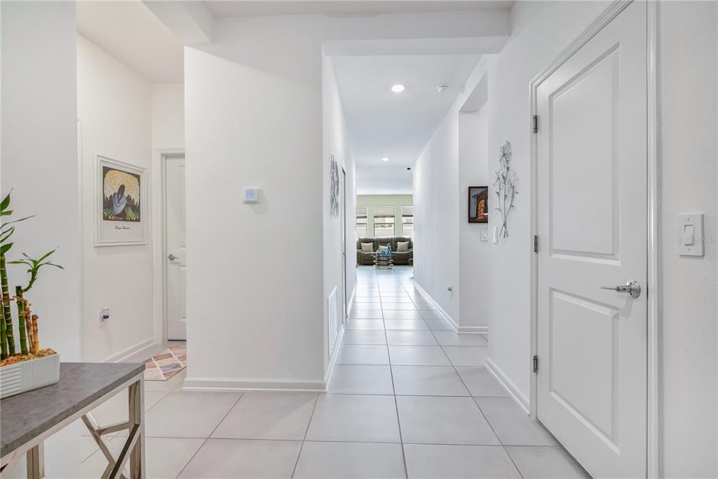 A bright hallway with white walls and light tile flooring leads toward a living area — 815 KAPI DRIVE, GROVELAND, FL