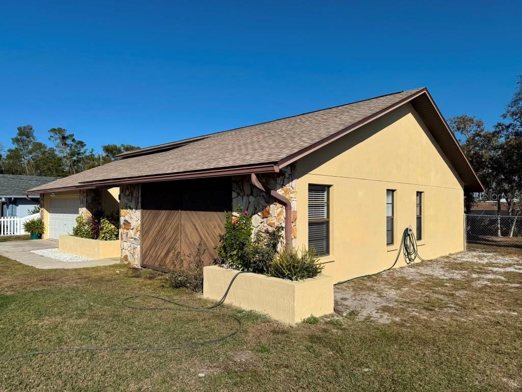 A side view of a yellow house with a stone facade and a garage — 5389 FROST ROAD, SPRING HILL, FL