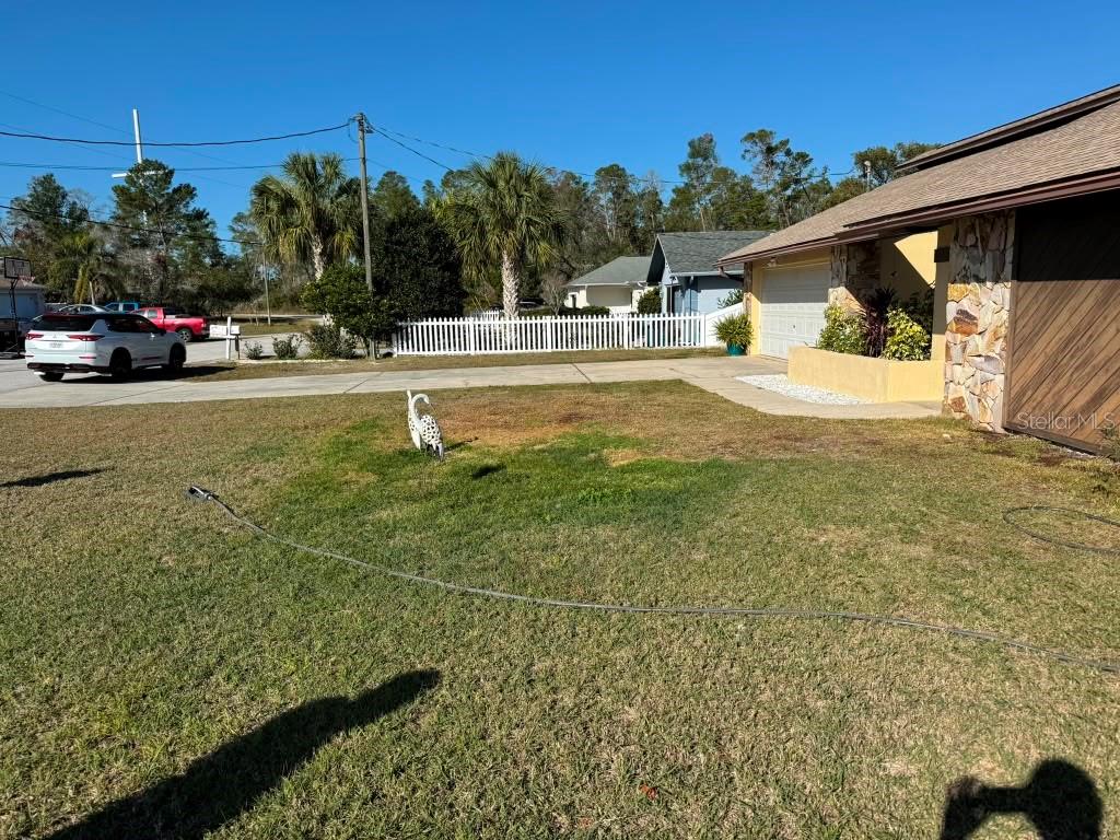 A front yard with a lawn, a decorative bird statue, and a house with stone accents — 5389 FROST ROAD, SPRING HILL, FL
