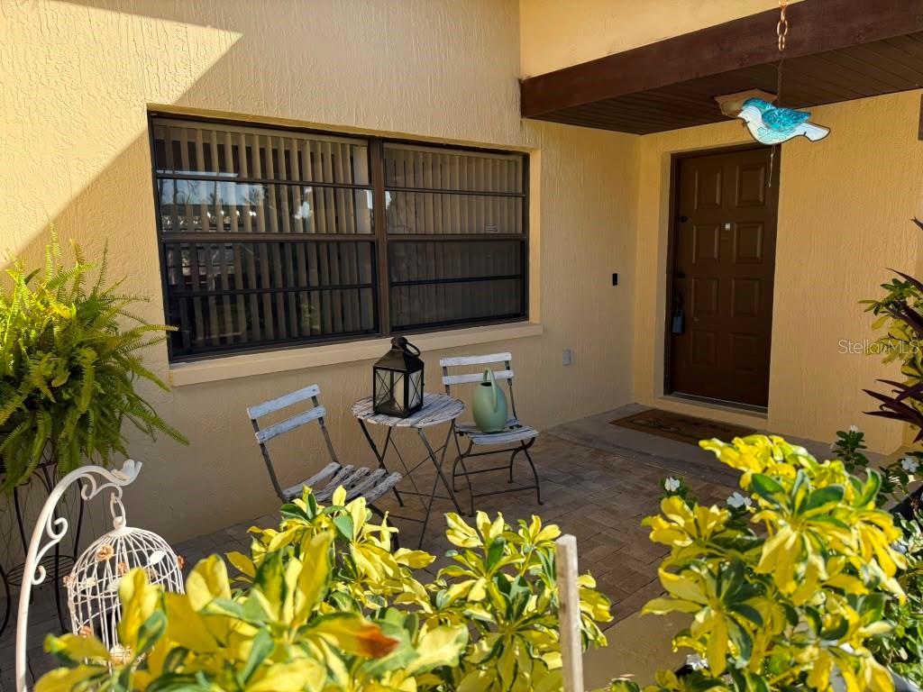 A patio features a small table and two chairs in front of a house entrance — 5389 FROST ROAD, SPRING HILL, FL