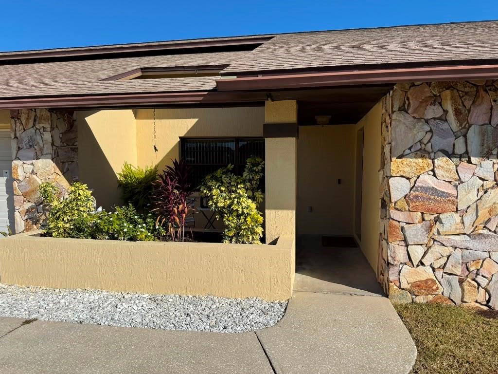 The exterior of a house features a stone facade, a concrete walkway, and a planter box — 5389 FROST ROAD, SPRING HILL, FL