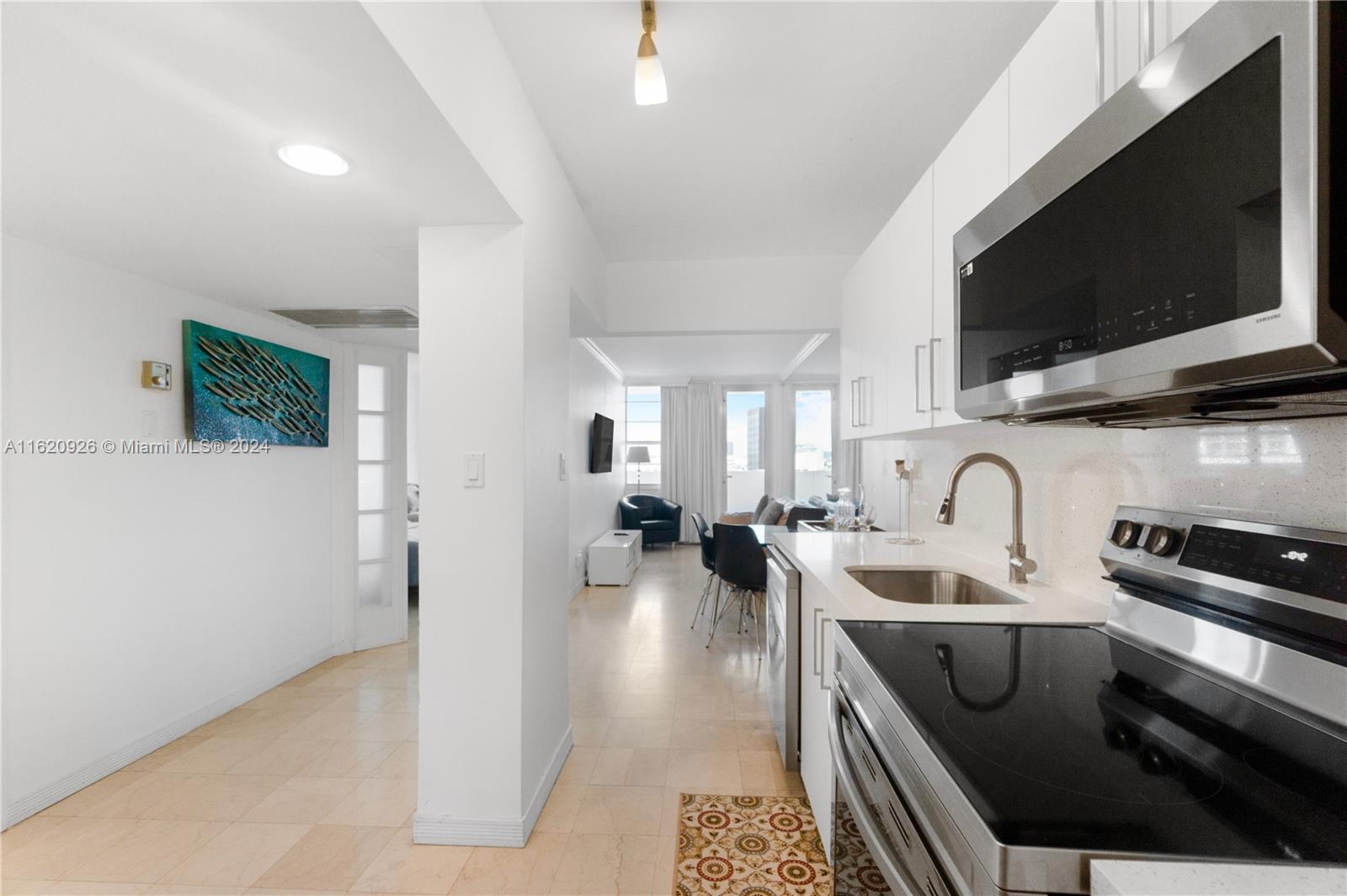 A modern kitchen with stainless steel appliances opens into a bright living area — 100 Lincoln Rd # 820, Miami Beach FL 33139, MIAMI BEACH, FL
