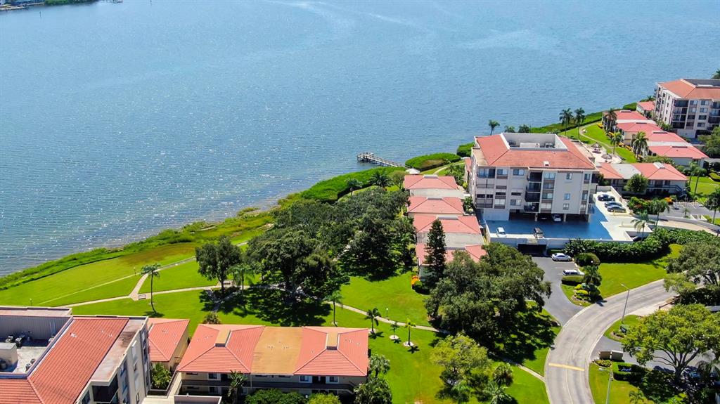 An aerial view shows waterfront apartment buildings with red roofs surrounded by green lawns — 6218 PALMA DEL MAR BOULEVARD S UNIT 606, ST PETERSBURG, FL