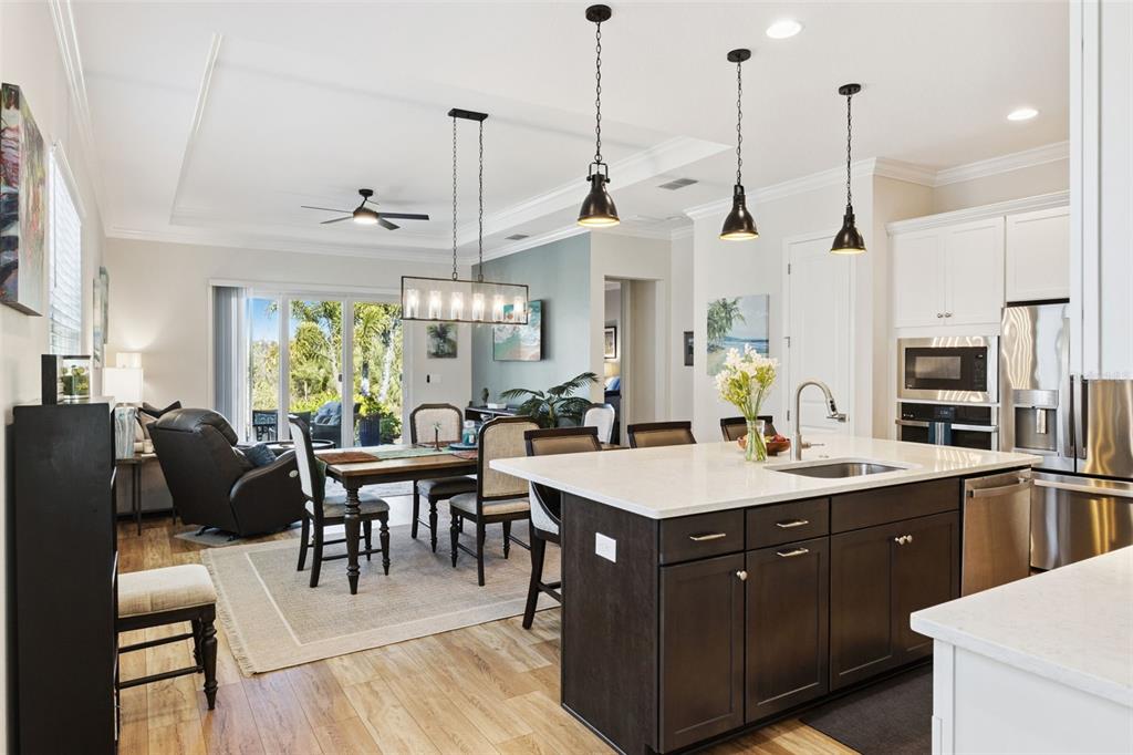A kitchen with a dark island and white cabinets opens to a dining area and living room — 7637 SAND PIERRE COURT, KISSIMMEE, FL