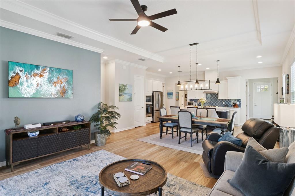 An open-concept living and dining area features wood flooring, a ceiling fan, and white cabinetry — 7637 SAND PIERRE COURT, KISSIMMEE, FL