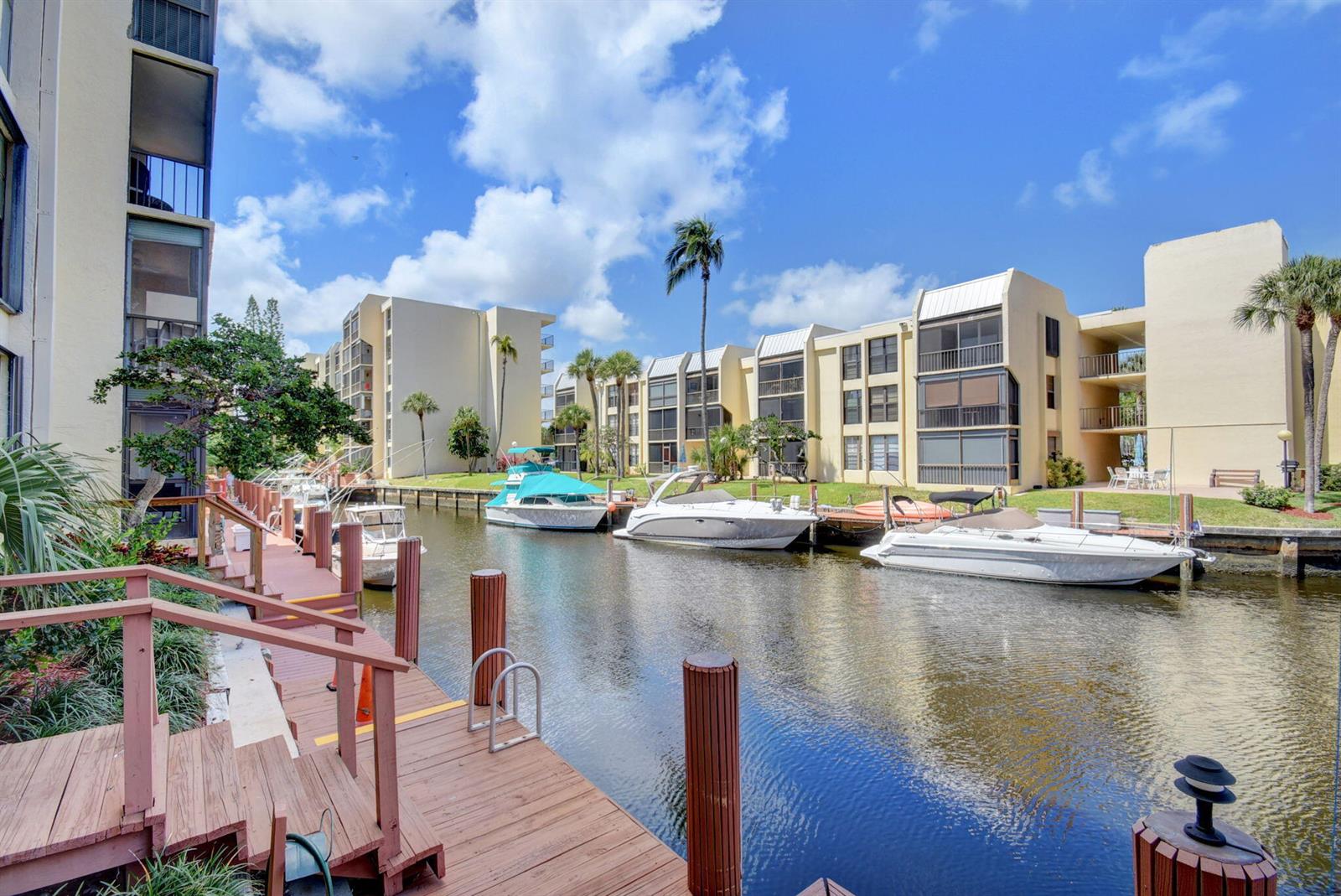 A wooden dock overlooks a canal with several docked boats and multi-story apartment buildings — 4 Royal Palm Way # 601, Boca Raton FL 33432, BOCA RATON, FL