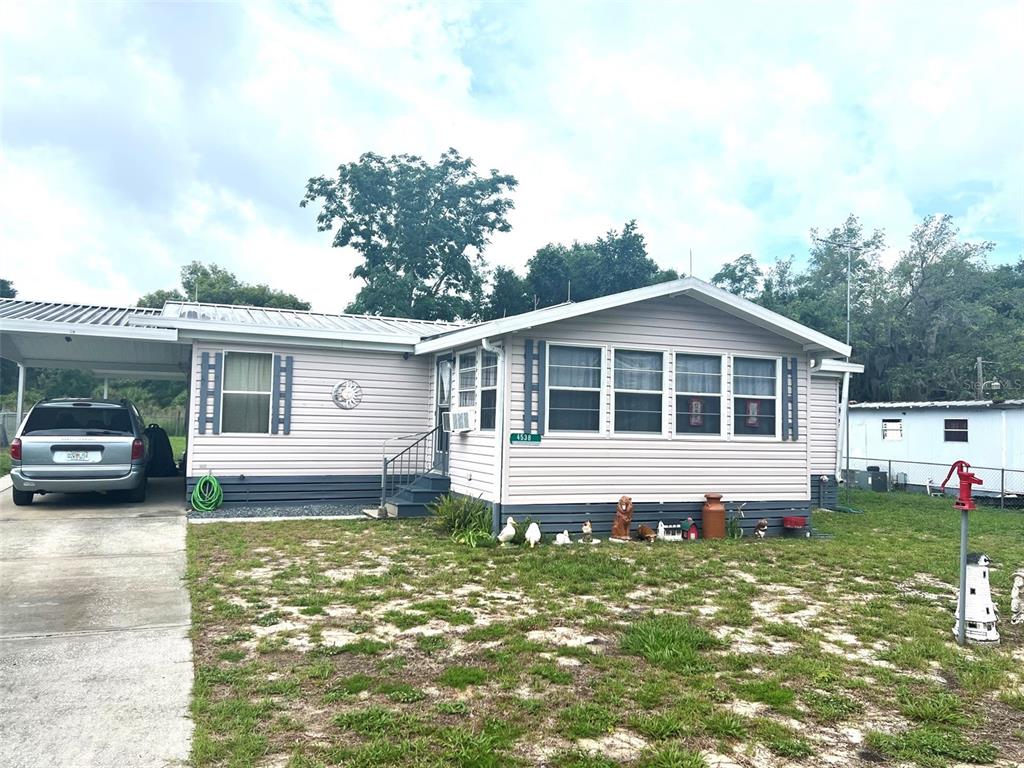 A light-colored mobile home with a carport and a front yard — 4538 OAK STREET, FRUITLAND PARK, FL