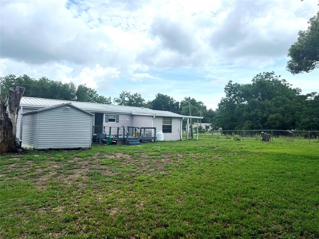 A light-colored single-story house with a metal roof and an attached shed in a yard — 4538 OAK STREET, FRUITLAND PARK, FL