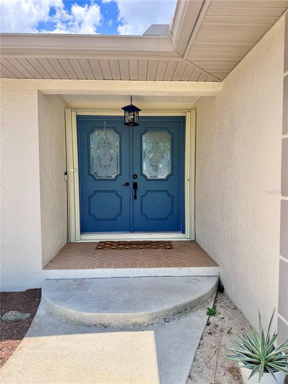 A blue double front door with glass inserts sits under a covered entryway — 1087 BAY HARBOR DRIVE, ENGLEWOOD, FL