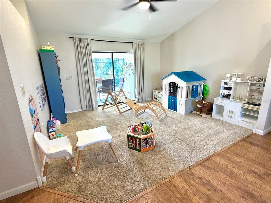 A carpeted playroom features a playhouse, a wooden climbing set, and a toy kitchen — 1087 BAY HARBOR DRIVE, ENGLEWOOD, FL