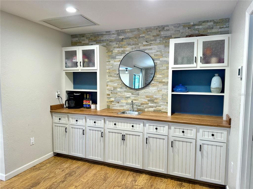 A wet bar features white cabinets, a wood countertop, and a stone tile backsplash — 1087 BAY HARBOR DRIVE, ENGLEWOOD, FL
