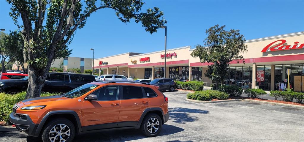 An orange Jeep is parked in front of a strip mall with several retail storefronts — 2019 E SILVER SPRINGS BOULEVARD, OCALA, FL