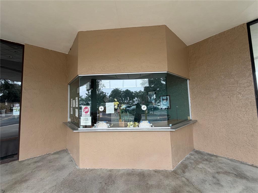 A beige exterior wall features a large glass service window with a metal counter — 2019 E SILVER SPRINGS BOULEVARD, OCALA, FL