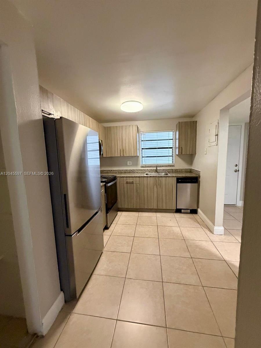 A kitchen features light wood cabinets, granite countertops, stainless steel appliances, and tile flooring — 2111 NW 55th Ave # 211, Lauderhill FL 33313, LAUDERHILL, FL