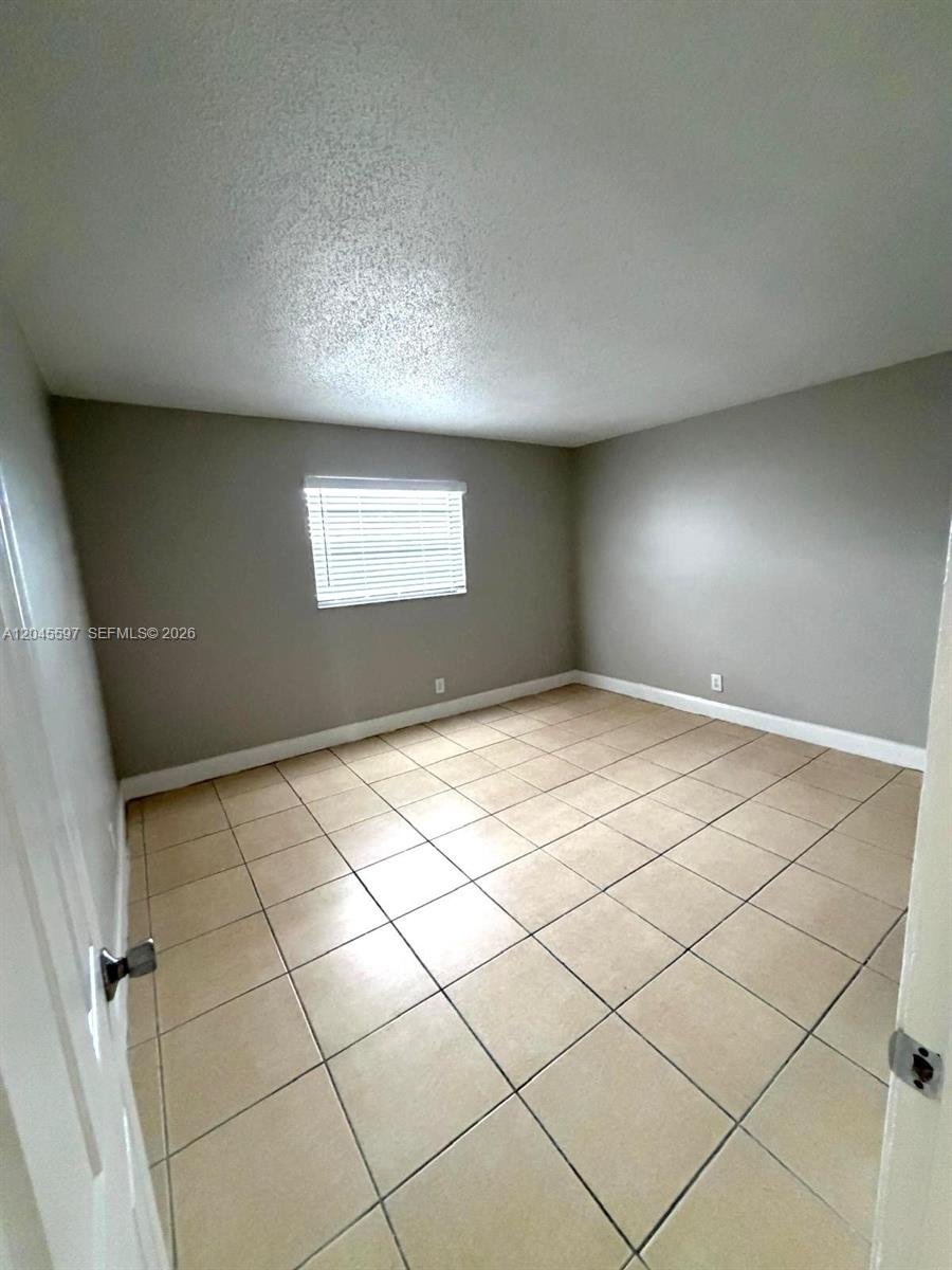 This room features beige tile flooring, light gray walls, and a single window with blinds — 2111 NW 55th Ave # 211, Lauderhill FL 33313, LAUDERHILL, FL