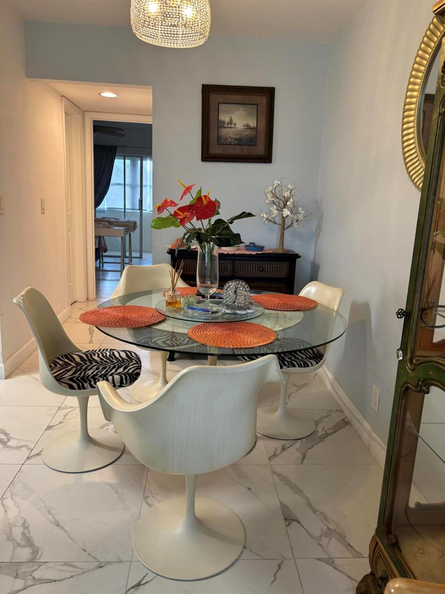 A dining area features a glass-topped table, four white pedestal chairs, and marble-look tile flooring — 325 Andover, West Palm Beach FL 33417, WEST PALM BEACH, FL