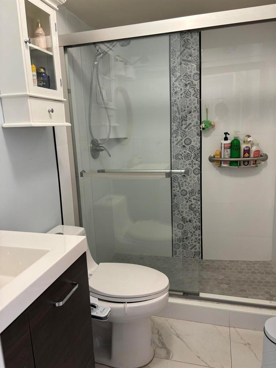 A bathroom features a glass-enclosed shower with patterned tile accents, a vanity, and a toilet — 325 Andover, West Palm Beach FL 33417, WEST PALM BEACH, FL