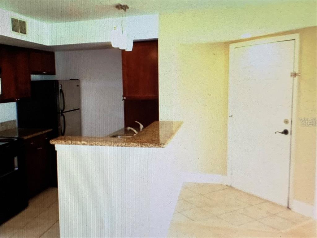 A kitchen with dark wood cabinets, granite countertops, and a breakfast bar — 5124 CONROY ROAD UNIT 635, ORLANDO, FL