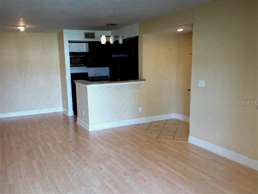 An interior view shows a living area with light wood floors leading to a kitchen — 5124 CONROY ROAD UNIT 635, ORLANDO, FL