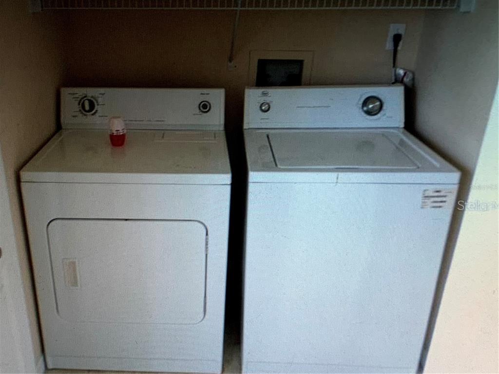 A white clothes dryer and a matching top-loading washing machine sit in a laundry closet — 5124 CONROY ROAD UNIT 635, ORLANDO, FL