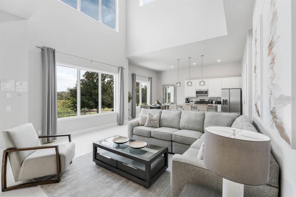 A bright living room features high ceilings, a large sectional sofa, and an open kitchen — 7760 SANDY RIDGE DRIVE UNIT 226, REUNION, FL