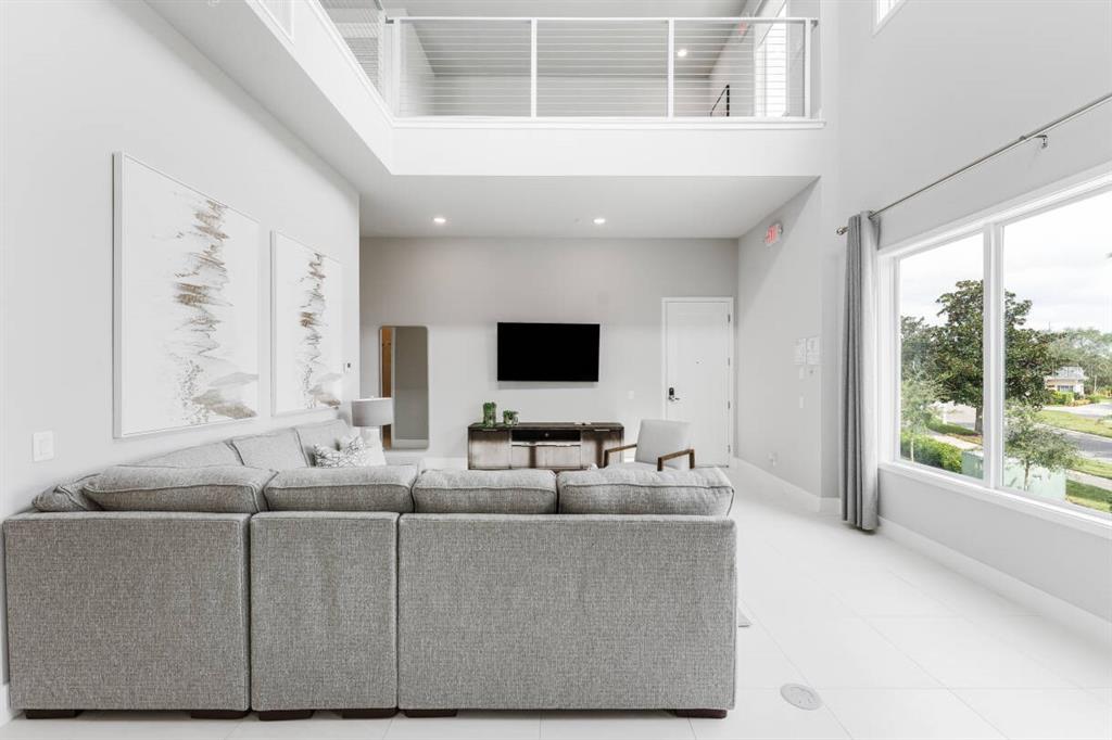 A living room with a gray sectional sofa, high ceilings, and large windows — 7760 SANDY RIDGE DRIVE UNIT 226, REUNION, FL