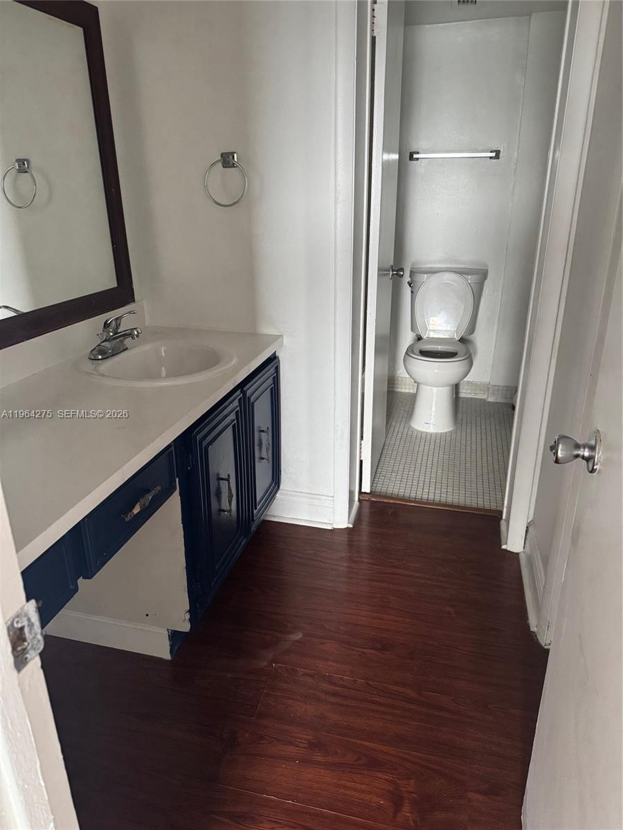 A bathroom features a vanity with a dark blue cabinet and a separate toilet area — 496 NW 165th St Rd # 614, Miami FL 33169, MIAMI, FL