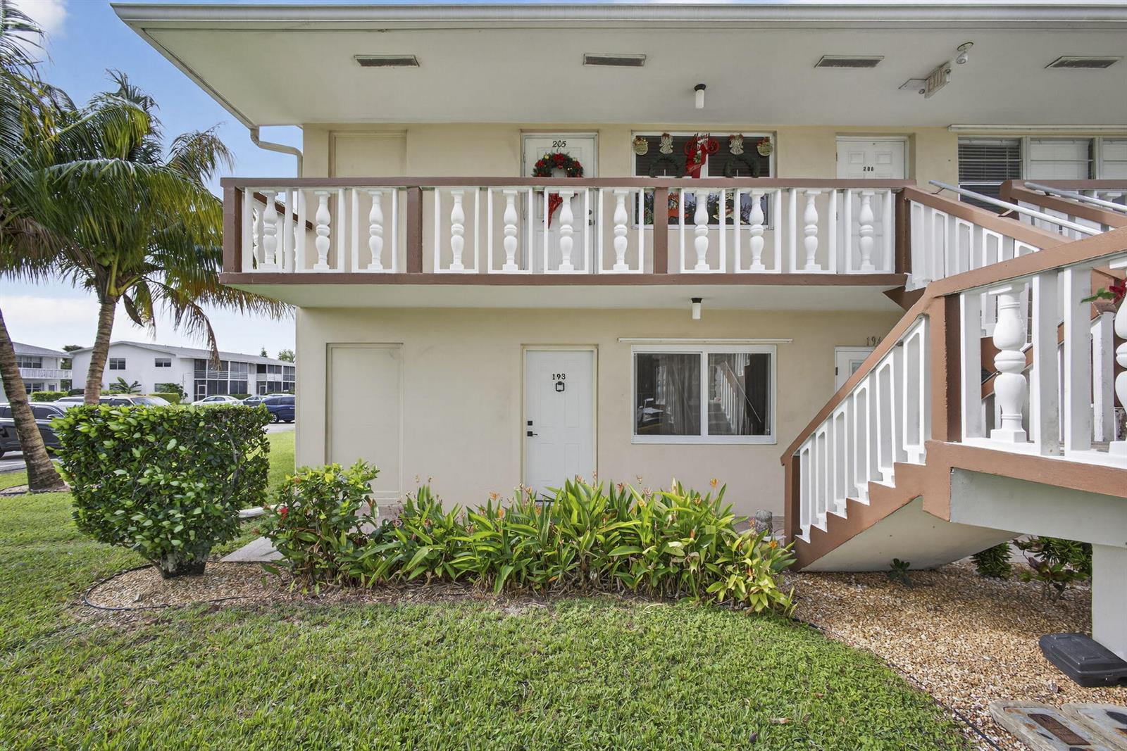 A two-story apartment building exterior features a white balcony, stairs, and ground-level unit entrances — 193 Easthampton I, West Palm Beach FL 33417, WEST PALM BEACH, FL