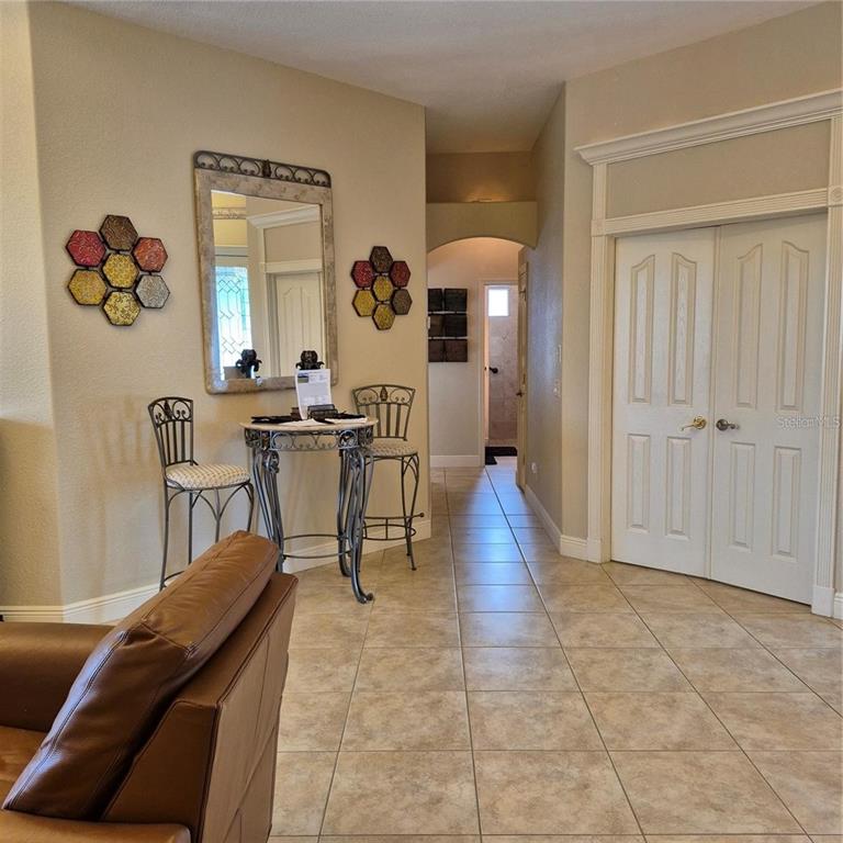A tiled entryway features a small bistro table, decorative wall art, and double doors — 19 MEDALIST WAY, ROTONDA WEST, FL