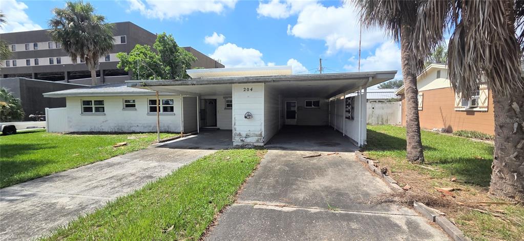 A single-story house with a large carport and a concrete driveway sits on a lawn — 204 BOBBIE CIRCLE, LAKELAND, FL