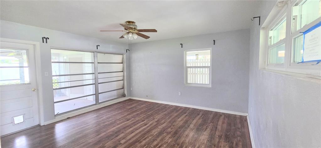 A room with wood-look flooring, a ceiling fan, and large windows overlooking a porch — 204 BOBBIE CIRCLE, LAKELAND, FL