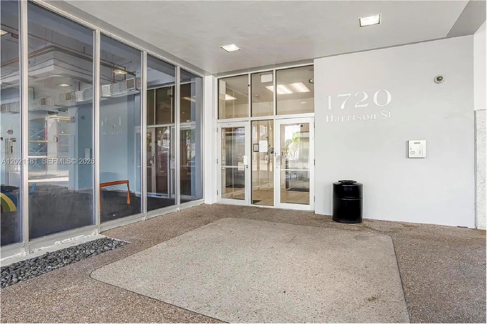 The exterior entrance features glass doors, large windows, and a concrete walkway — 1720 Harrison St # 5A, Hollywood FL 33020, HOLLYWOOD, FL