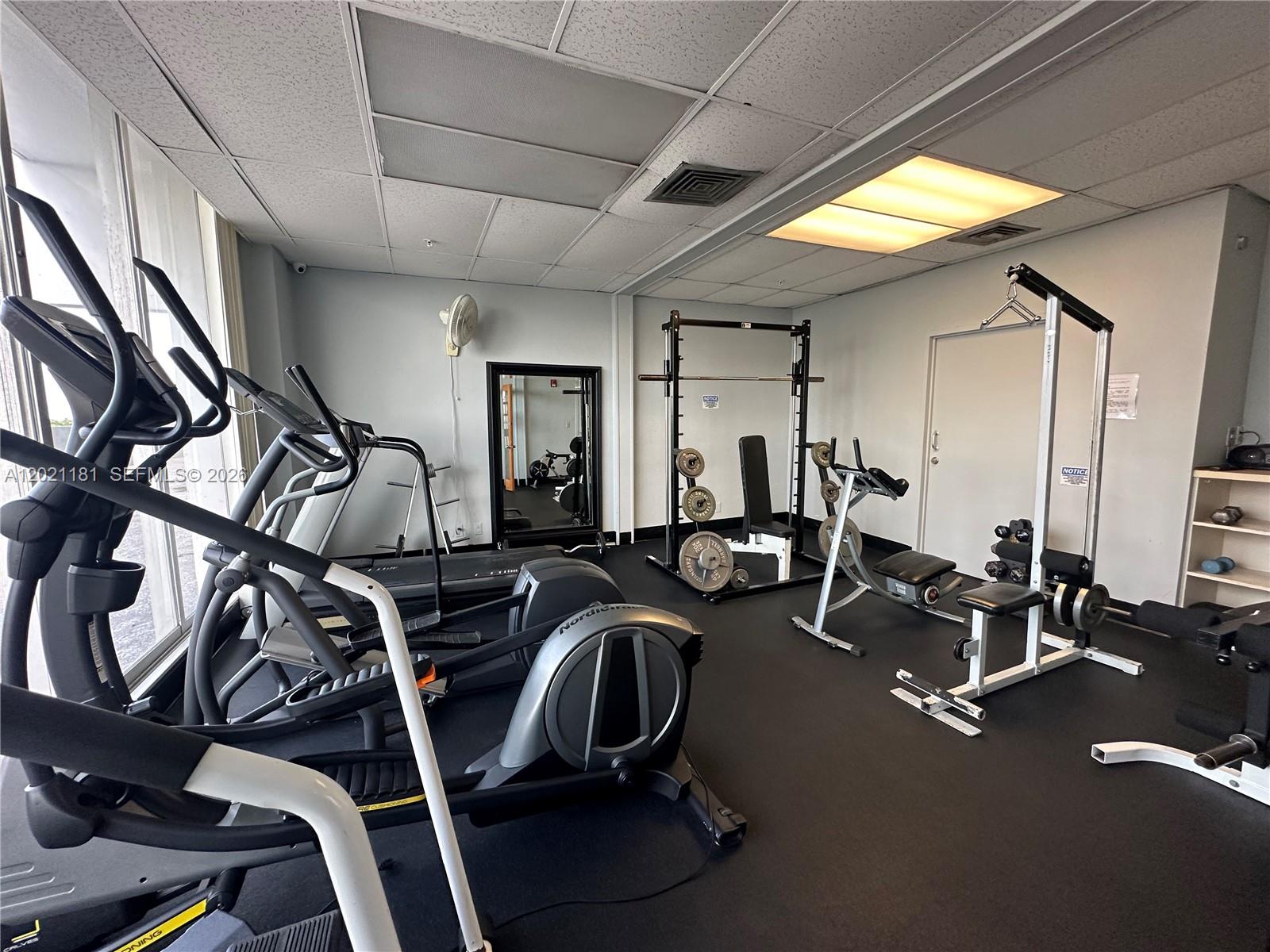A gym room features various exercise machines, a squat rack, and black rubber flooring — 1720 Harrison St # 5A, Hollywood FL 33020, HOLLYWOOD, FL