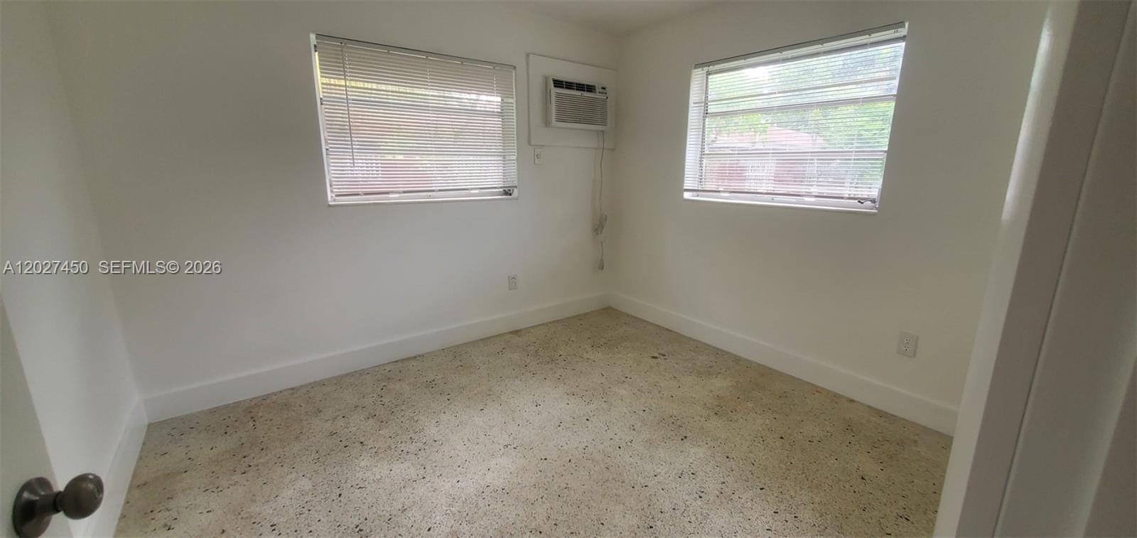 A small, empty room features white walls, two windows with blinds, and speckled flooring — 1032 SW 10th St, Miami FL 33130, MIAMI, FL
