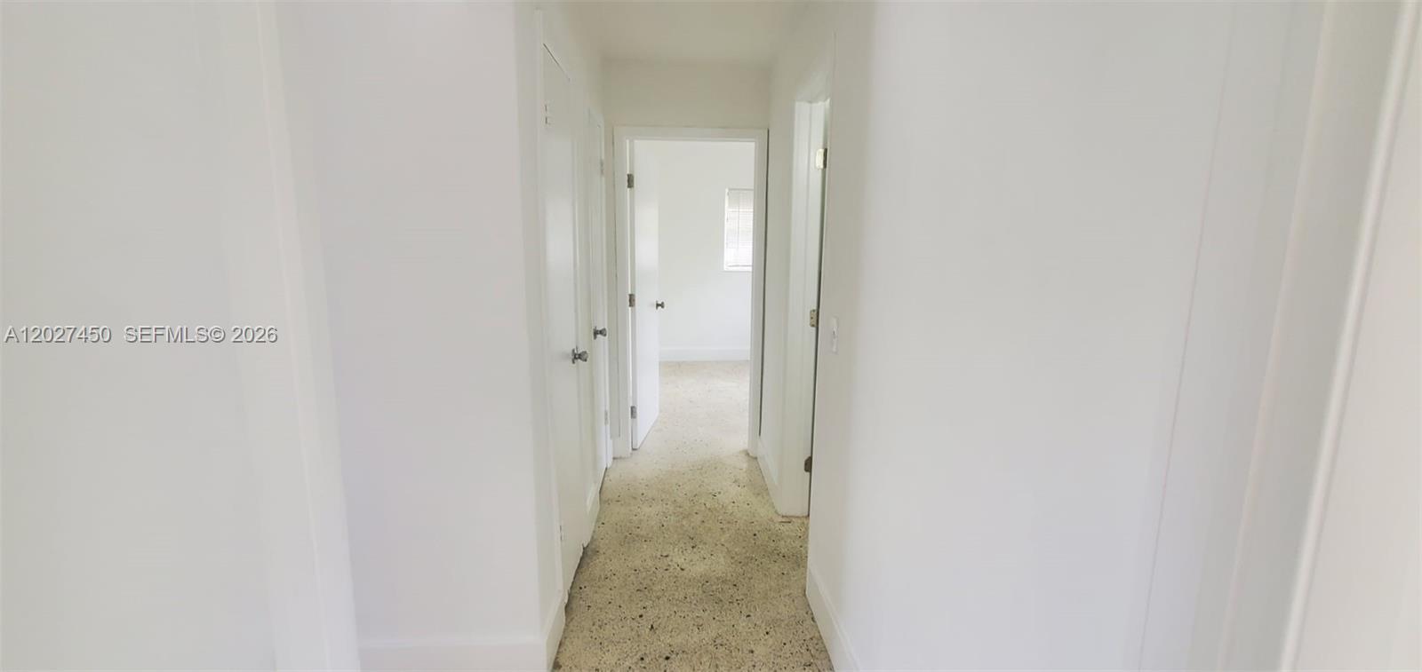 A narrow hallway with white walls, closed doors, and speckled flooring leads to a room — 1032 SW 10th St, Miami FL 33130, MIAMI, FL