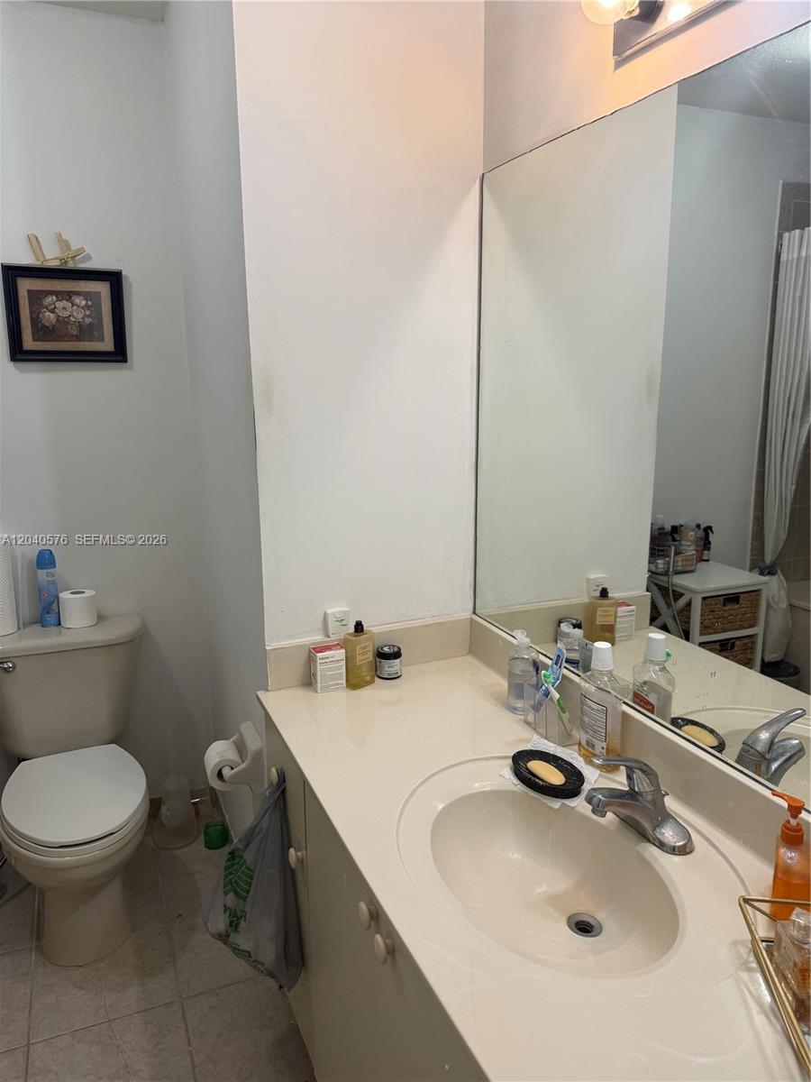 A bathroom features a toilet, a vanity with a sink, and a large wall mirror — 5943 SW 162nd Pl, Miami FL 33193, MIAMI, FL