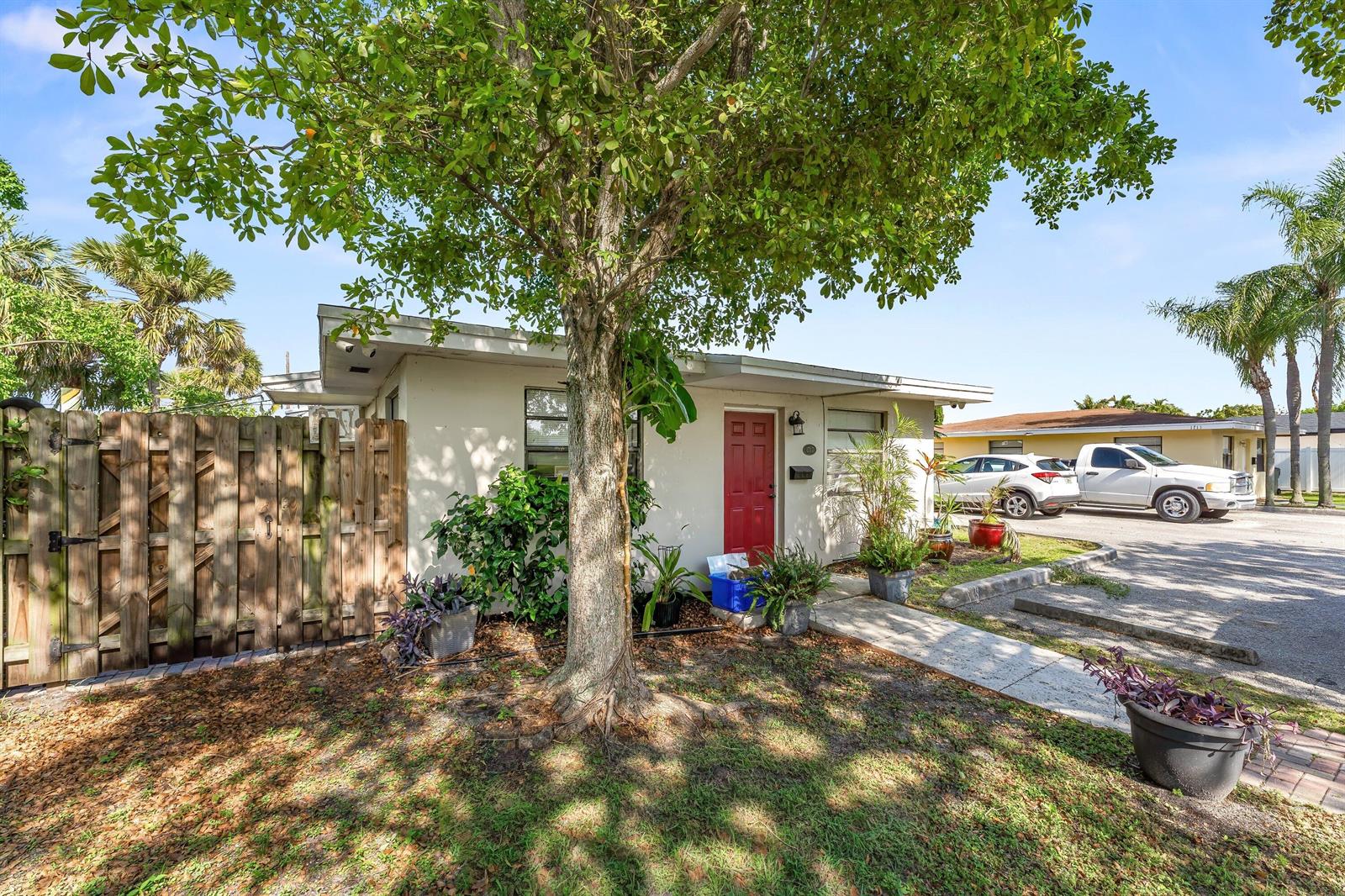 A single-story house with a red front door, a large tree, and a wooden fence — 1717 NE 3rd Avenue, Delray Beach FL 33444, DELRAY BEACH, FL