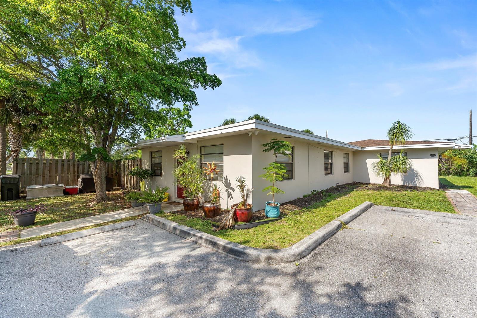 A single-story house with a flat roof, beige exterior, and potted plants in front — 1717 NE 3rd Avenue, Delray Beach FL 33444, DELRAY BEACH, FL