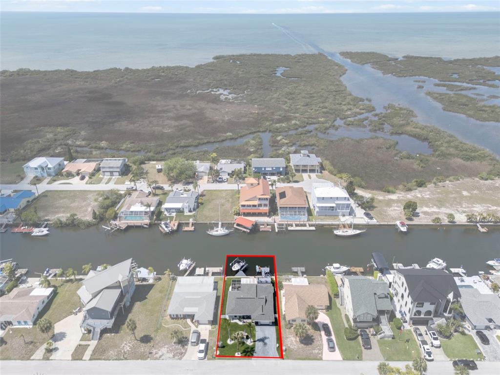 An aerial view shows a waterfront house with a boat dock on a canal — 15627 DONZI DRIVE, HUDSON, FL