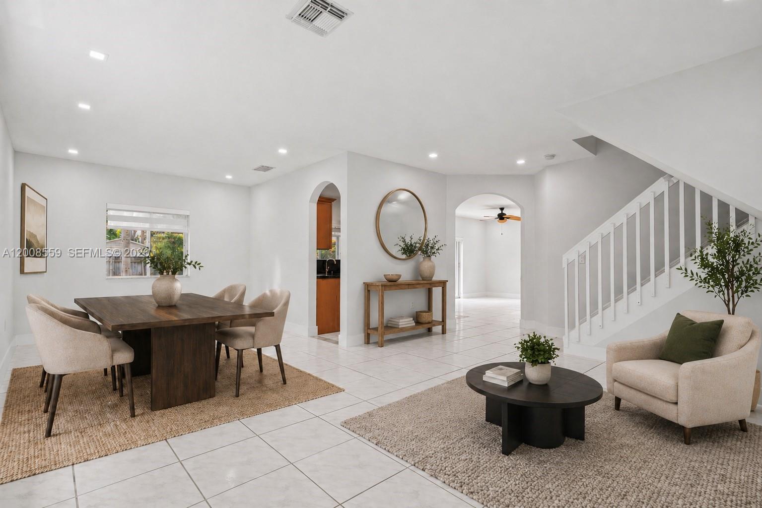 A dining area and seating space feature white tile floors, neutral furniture, and arched doorways — 9576 SW 162nd Path, Miami FL 33196, MIAMI, FL