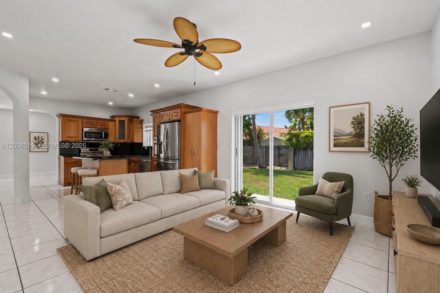 A living room with a beige sofa, green armchair, wooden coffee table, and open kitchen — 9576 SW 162nd Path, Miami FL 33196, MIAMI, FL